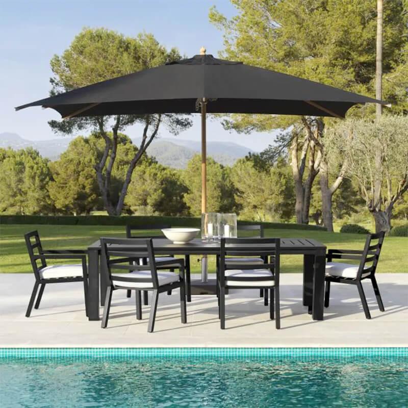 Eichholtz Vistamar black outdoor dining table, chairs, and umbrella poolside.